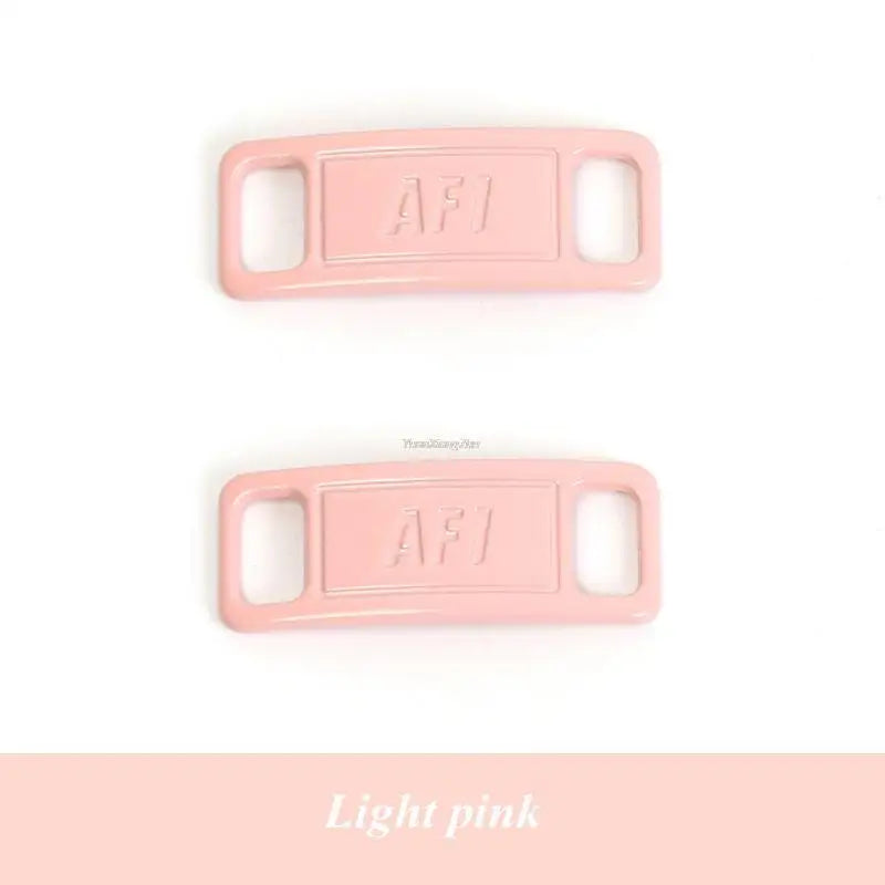 A light pink plastic charm with the letters AFJ stamped on it.