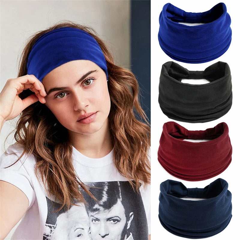 A woman models a navy blue boho knot headwrap hair band against a light background.
