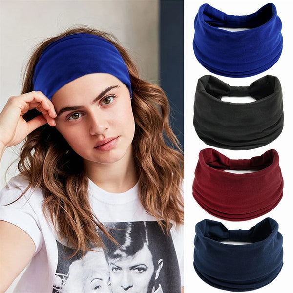 A woman models a navy blue boho knot headwrap hair band against a light background.