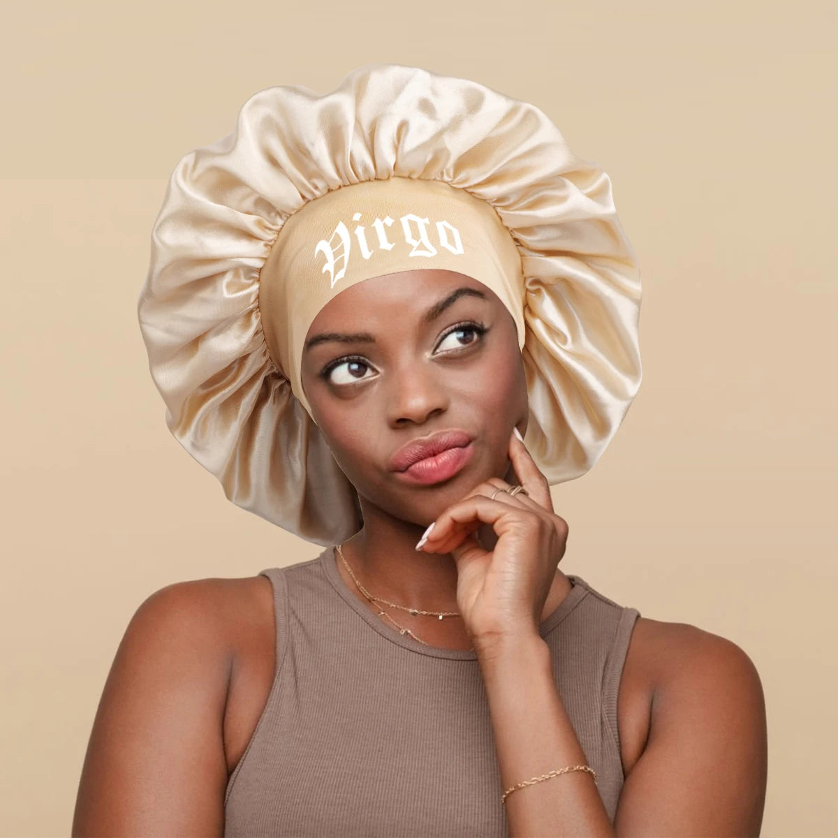 A woman wearing a satin sleep bonnet with a wrap band featuring the Virgo symbol.