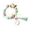 A silicone wristlet keychain featuring a Highland cow charm and green tassel.