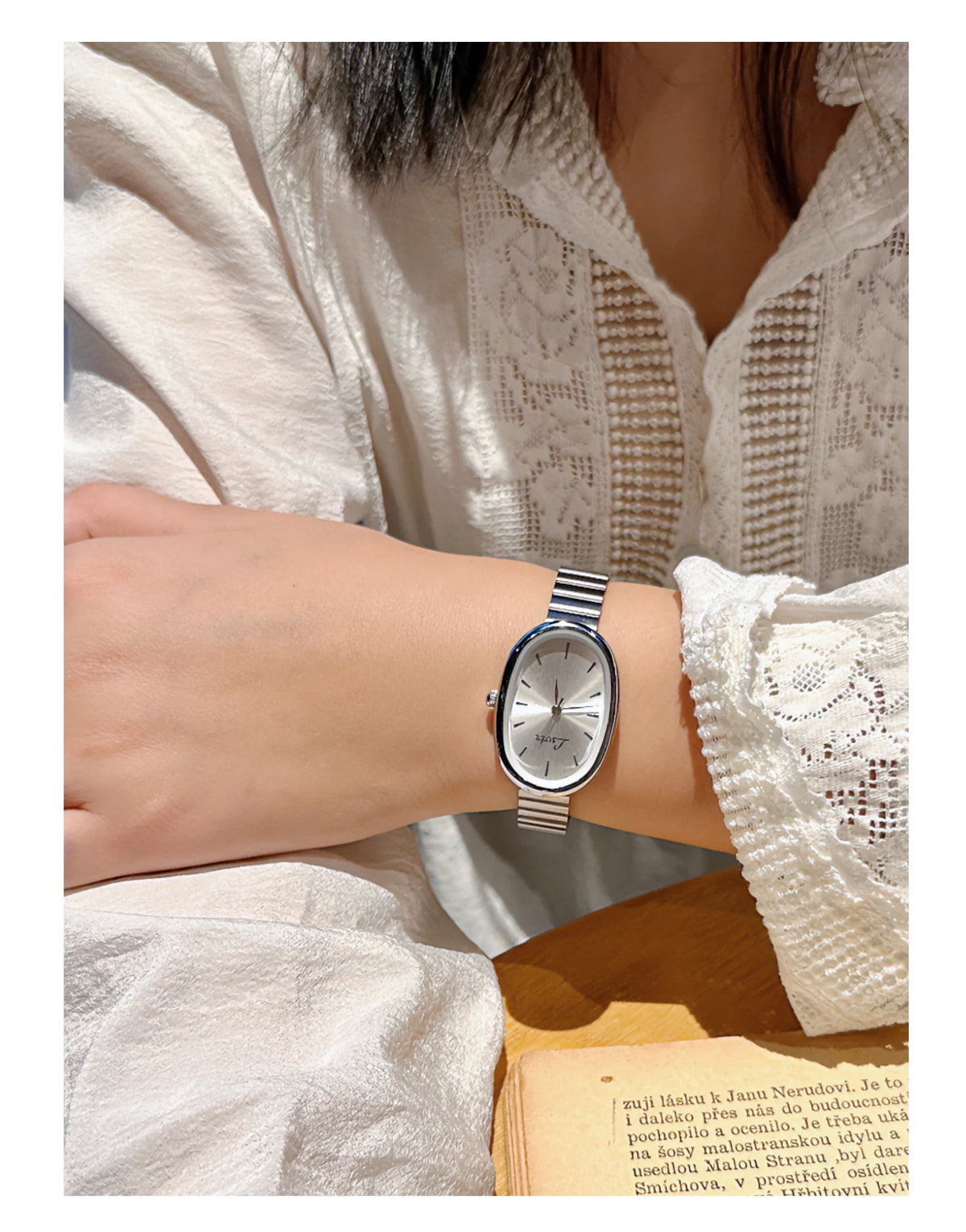 Gros plan d'une femme portant une élégante montre en quartz argent sur son poignet, associée à une manche en dentelle blanche