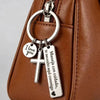 A silver stainless steel couple keychain with a cross and the engraved message I love you and Maneja con cuidado