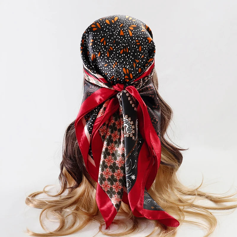 A black and orange patterned satin silk scarf tied around a woman's hair.