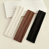 Three solid fabric headbands in cream, brown, and black are displayed on a light background.