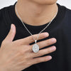A silver chain necklace with a round pendant featuring the Virgin Mary prayer design, worn against a black shirt.