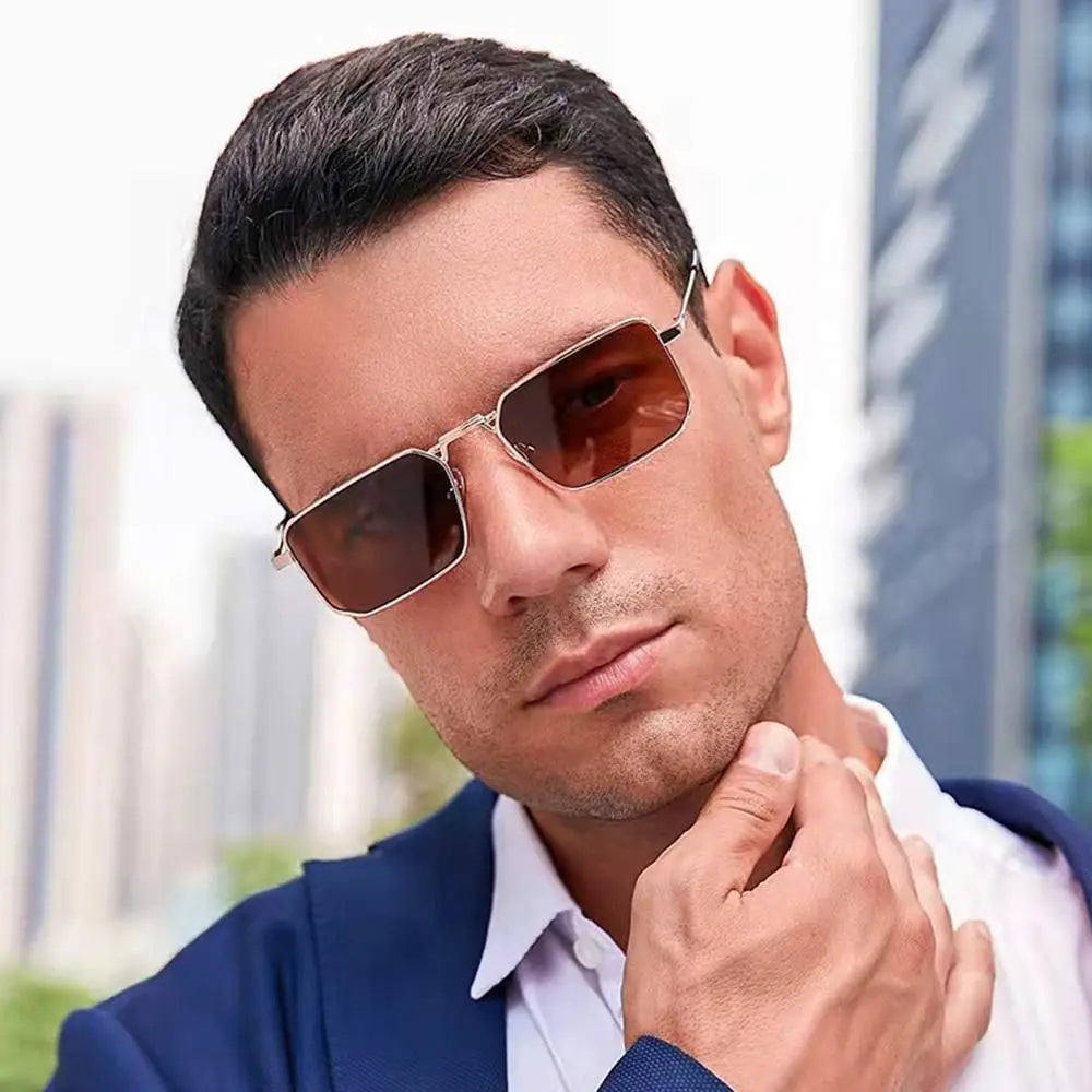 A man wearing retro vintage metal frame sunglasses and a blue suit jacket.