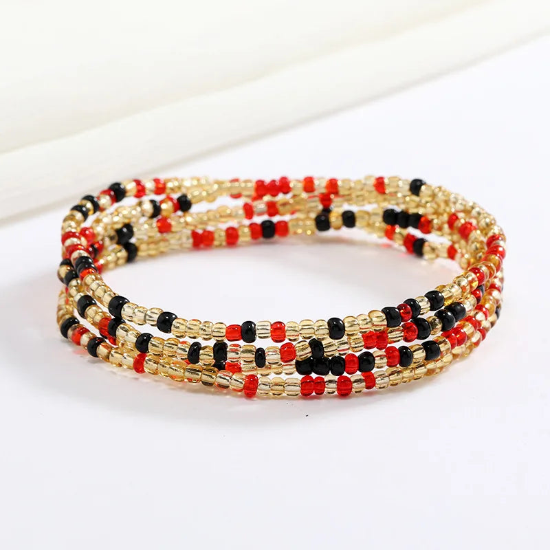 Una pulsera hecha de cuentas pequeñas rojas, negras y doradas apiladas.