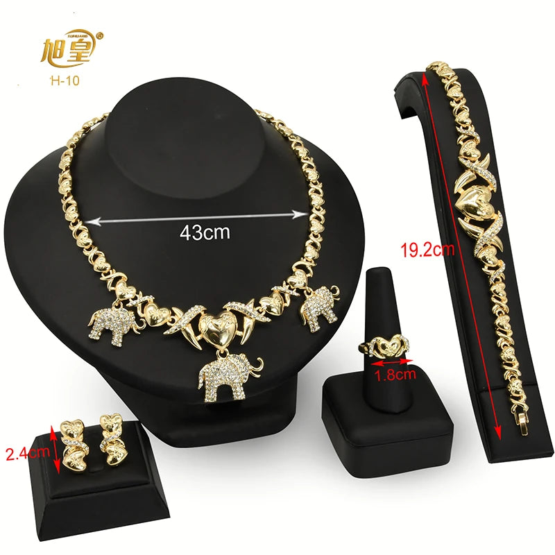 A set of 18K gold heart crystal jewelry including a necklace, pendant, and earrings displayed on a black stand.