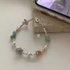 Sterling silver double heart charm bracelet featuring various colored stones and pearl accents