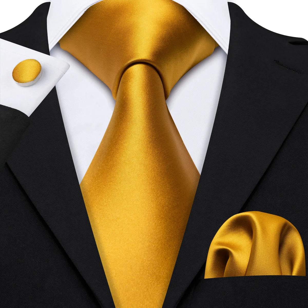 A black suit jacket with a gold silk tie and a white shirt, featuring a gold cufflink.
