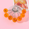 A set of orange, star-shaped acrylic keychains attached to a silver chain and ring, displayed on a pink background.