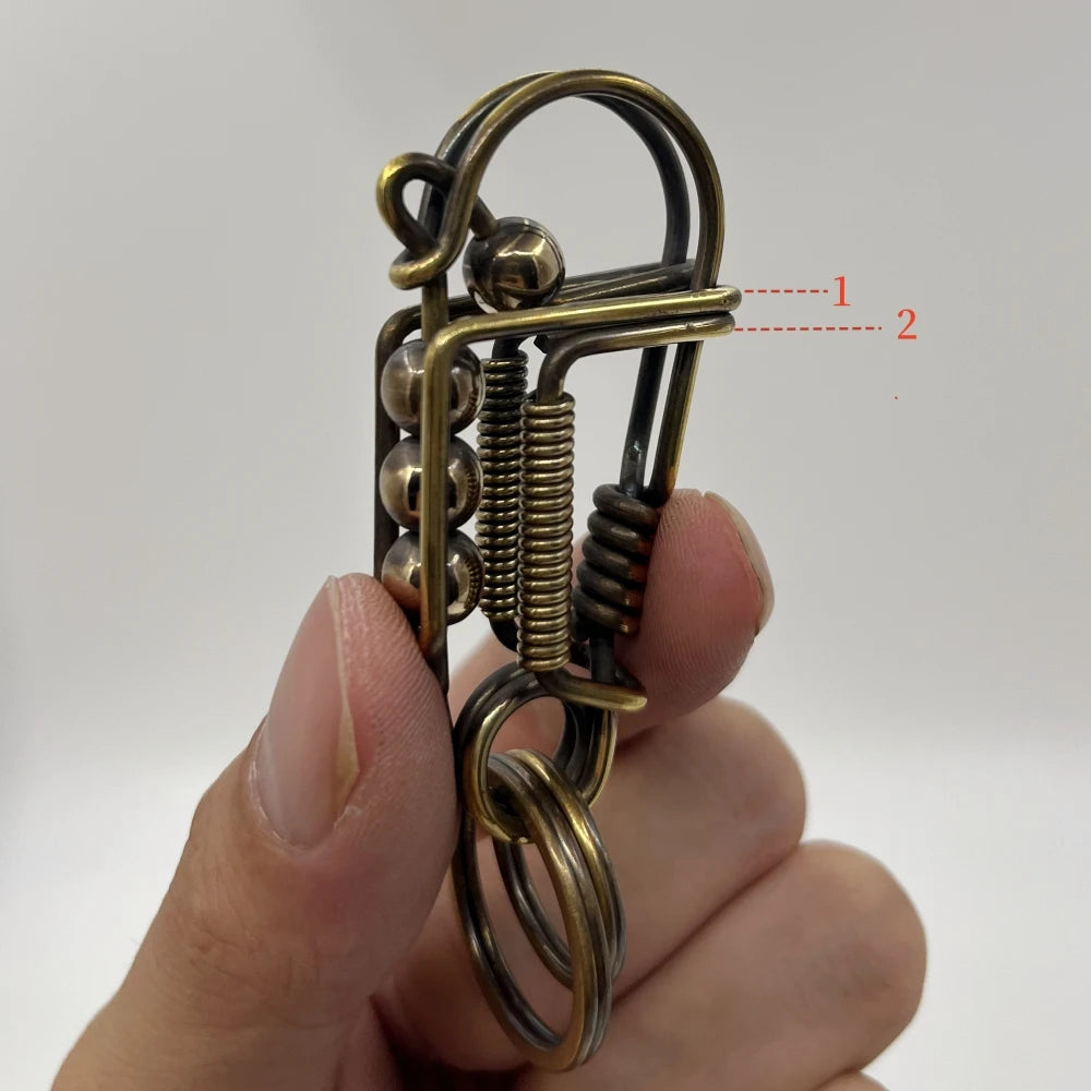 Gros plan d'une clé mécanique en acier inoxydable avec ressort et boucle, tenue par les doigts d'une personne.