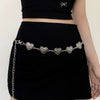 A woman wearing a black skirt and top with a silver heart chain body jewelry accessory.