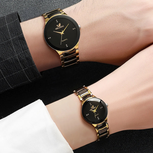 A pair of gold-toned analog quartz watches on a wrist against a dark background.