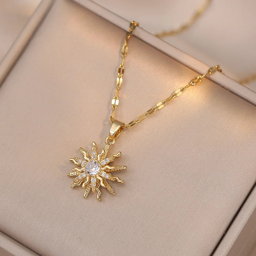Collier en or avec pendentif de fleur zircon soleil, présenté sur une boîte de couleur claire.