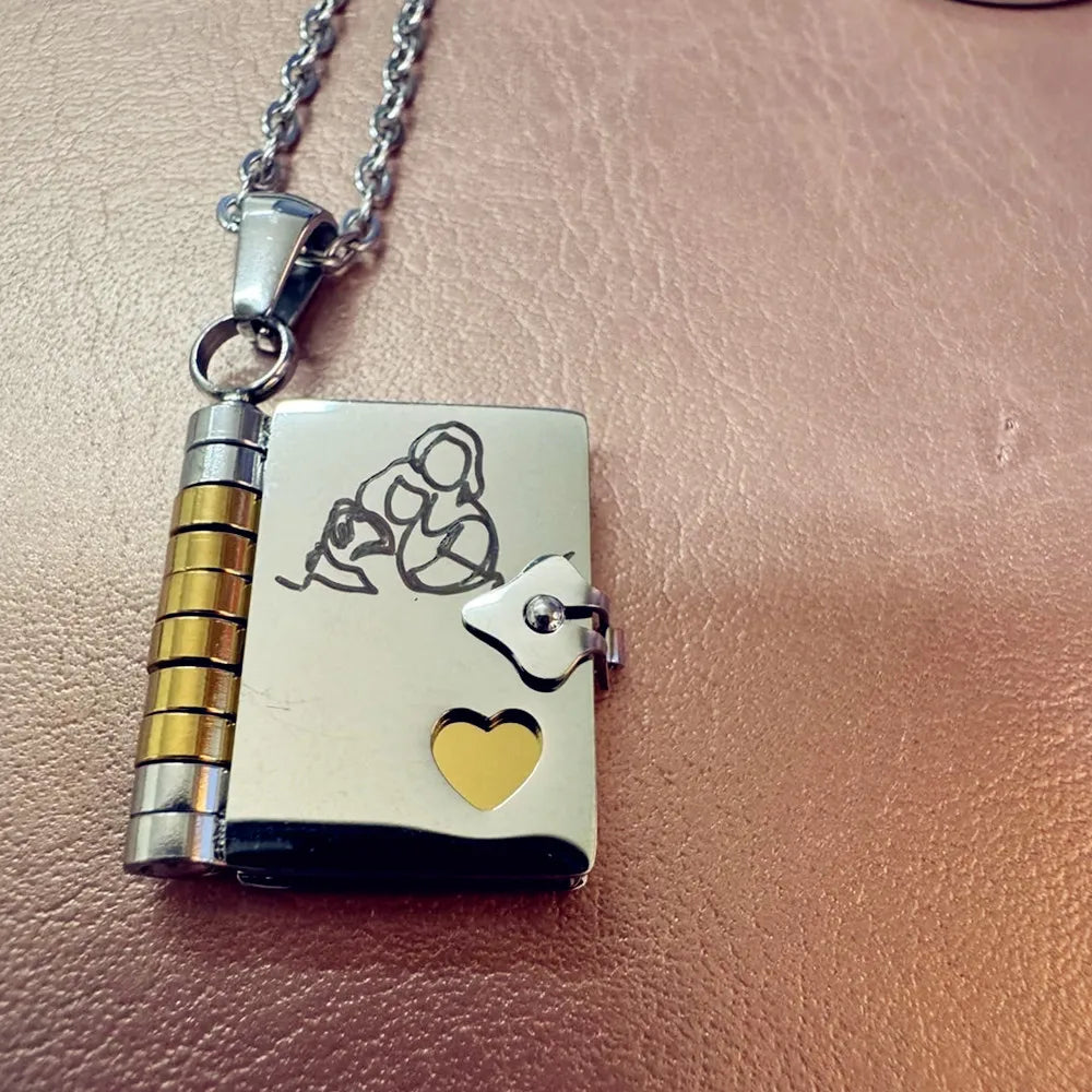 Silber-Anhänger-Kette mit goldenem Herz und Gravur auf rosa Leder.