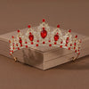 A sparkling crystal baroque bridal tiara featuring red gemstones and intricate silver-toned metalwork.