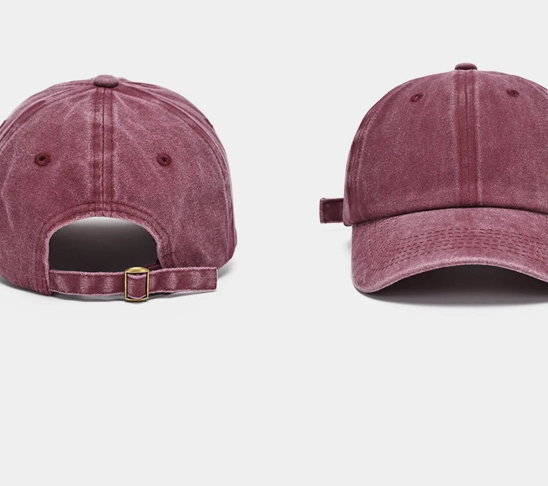 A close-up view of a dusty rose washed cotton snapback cap with a gold-toned buckle detail.