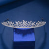 A sparkling cubic zirconia bridal tiara headband displayed on a blue velvet box against a dark blue background.