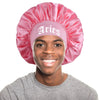 A young man wearing a pink satin sleep bonnet with an Aries wrap band.