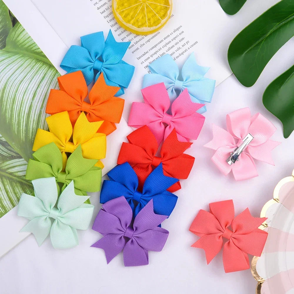 Assorted grosgrain ribbon hair bow clips in various colors like orange pink blue and green arranged on a white background.