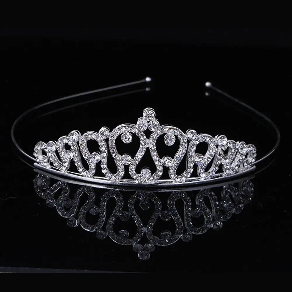 A sparkling crystal hair crown for women displayed on a black reflective surface.