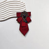 A deep red satin tie with a black diamond embellishment and a white striped fabric background.