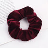 A close-up photo of a deep burgundy velvet scrunchie, showing its texture and gathered fabric.