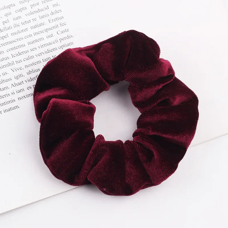 A close-up photo of a deep burgundy velvet scrunchie, showing its texture and gathered fabric.