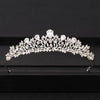 A delicate silver-toned crystal bridal crown with intricate floral and jewel designs.