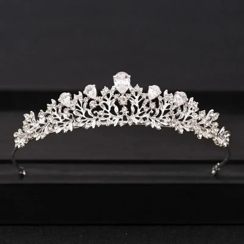 A delicate silver-toned crystal bridal crown with intricate floral and jewel designs.