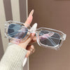 A hand holds a pair of clear plastic retro square fashion sunglasses with blue tinted lenses.