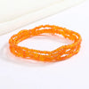 Pulsera de cadena corporal con cuentas naranjas, extendida sobre fondo blanco.
