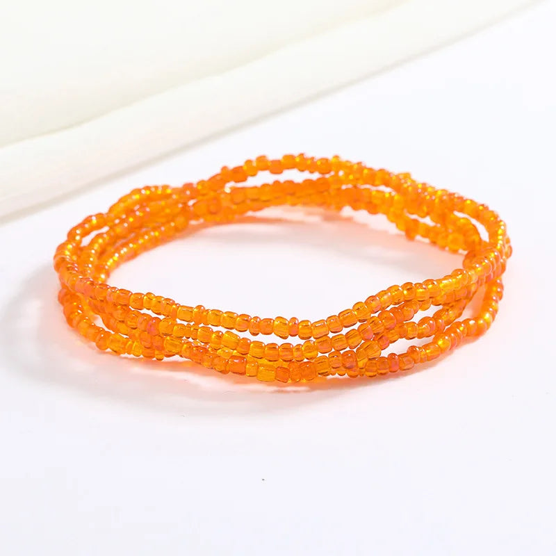 Pulsera de cadena corporal con cuentas naranjas, extendida sobre fondo blanco.