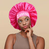 A woman wearing a pink satin sleep bonnet with a Taurus wrap band.