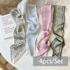 A set of four silk satin hair and bag accessories in various shades of gray and pink