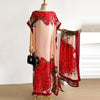 Une femme portant une robe rose fluide avec un châle cape à motif papillon et paon floral rouge drapé sur son épaule.