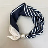 Navy and white striped silk scarf tied in a knot with a pearl magnetic clasp