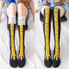 Pair of black socks with yellow chicken print and white cuff, shown on legs.