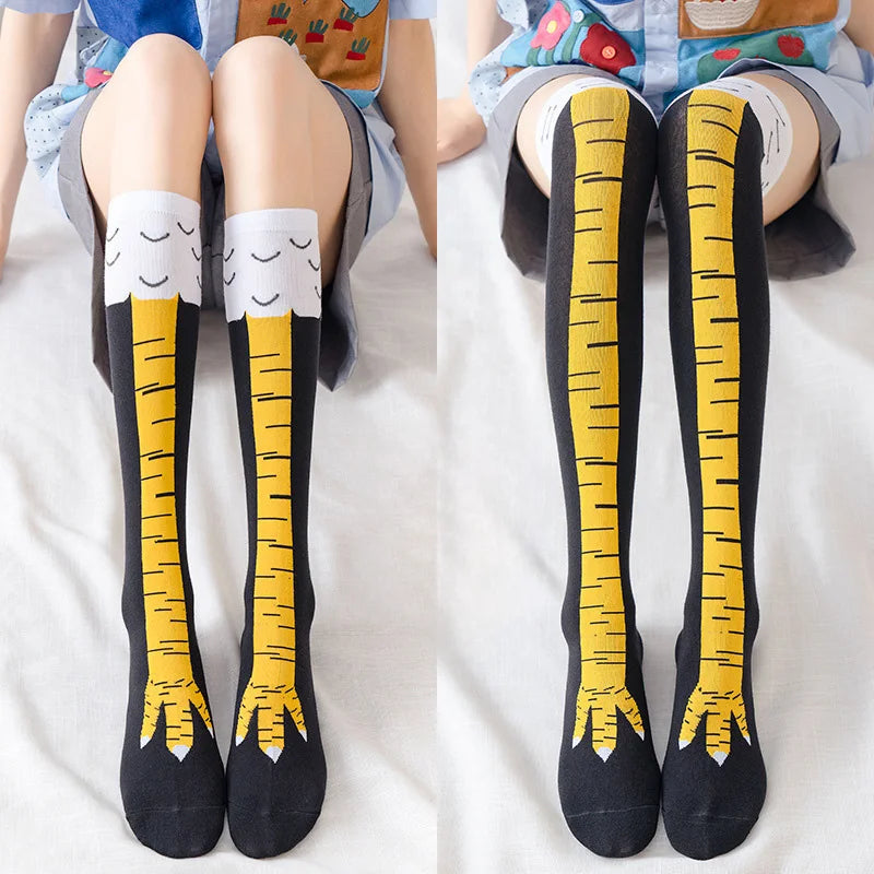 Pair of black socks with yellow chicken print and white cuff, shown on legs.