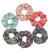 Un set de seis gomas de tela con estampado floral de satén en varios colores y patrones dispuestos en un círculo.