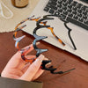 A hand holds a brown resin wave toothed headband with black accents against a white laptop.