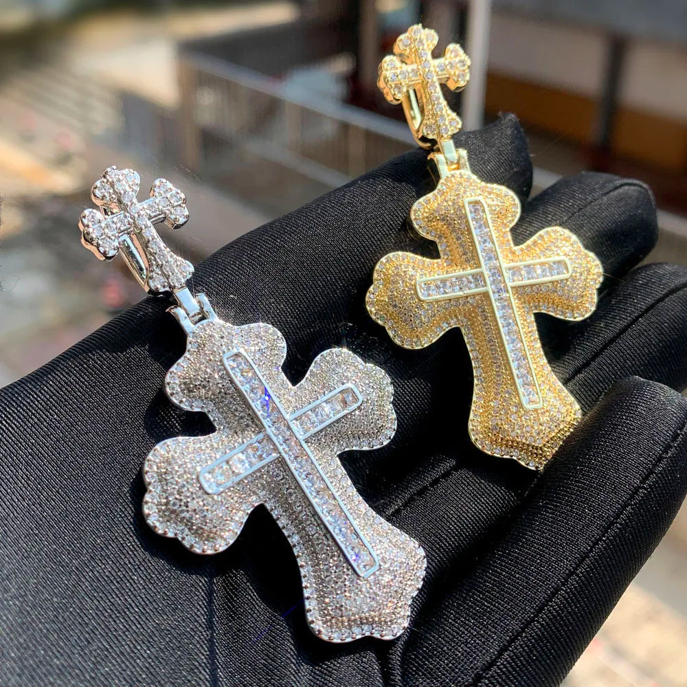 Un collier pendentif en croix serti d'or et d'argent, présenté sur un gant noir.