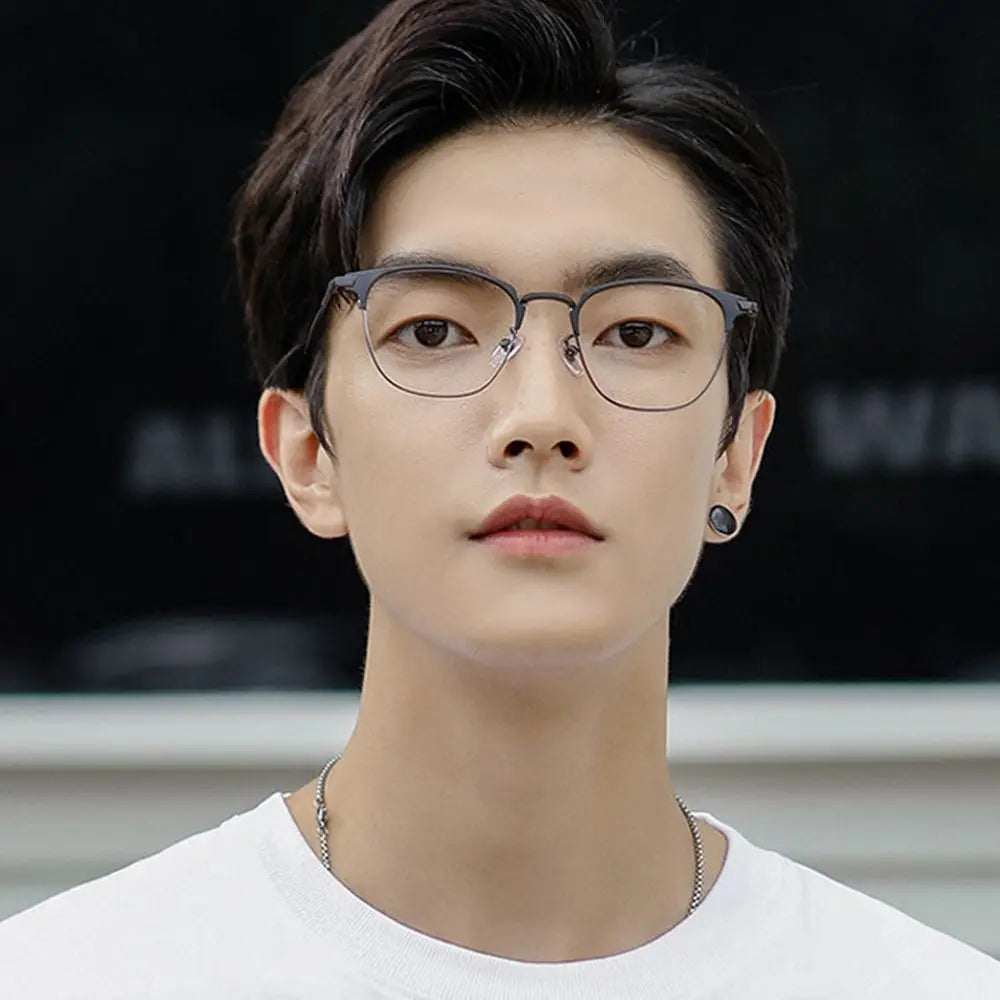 A close-up portrait of a young man wearing thin, silver-framed anti-blue light metal eyewear.