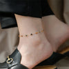 A close-up of a hand wearing a delicate gold and turquoise beaded bracelet on the wrist.