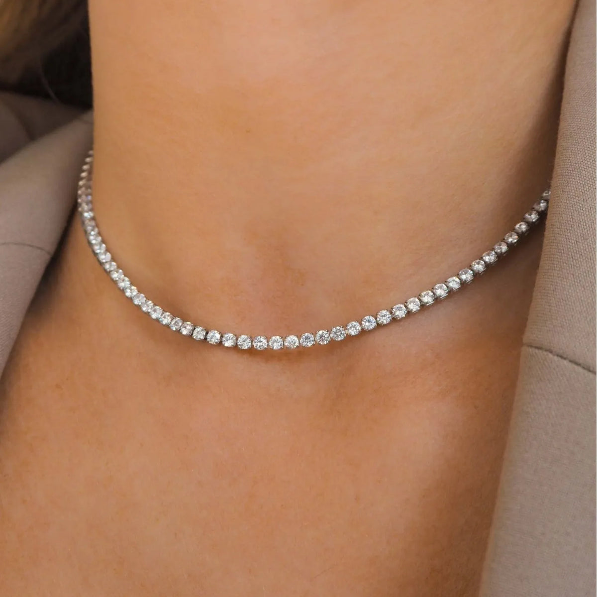 Primer plano de un collar de solitaria de diamantes usado alrededor del cuello en la piel de una persona.