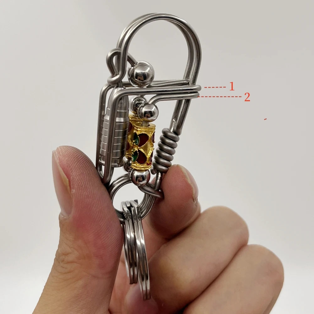 Une main tient une clé mécanique en acier inoxydable avec un charm doré et des pièces d'argent.