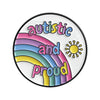 An enamel lapel pin featuring a rainbow design with the text autistic and proud and a sun symbol.