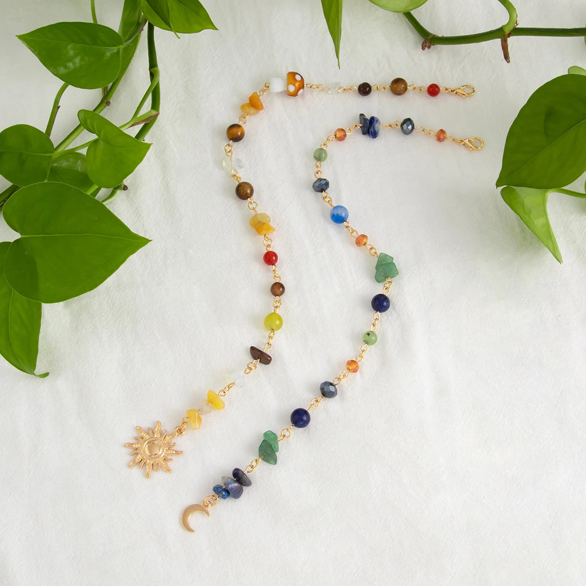 A delicate gold beaded necklace featuring various colored gemstones and a crescent moon charm.